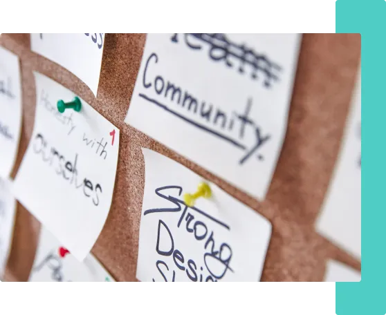 Cork board covered in sticky notes reading Community and Strong Design: a digital marketing strategy session